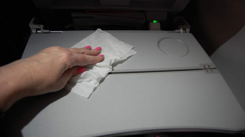 Person wiping plane tray table