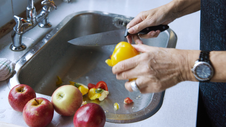 person cutting food at sink