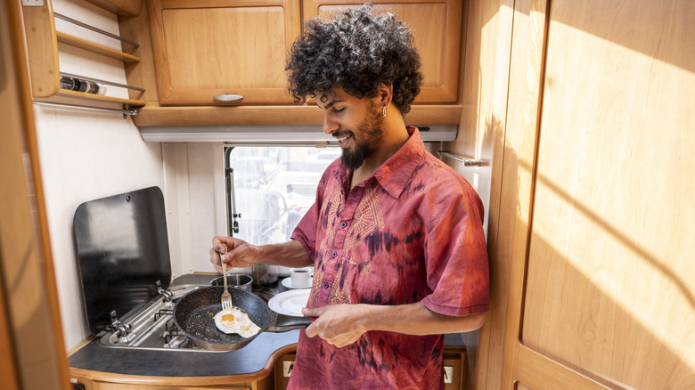 Man cooking eggs in camper