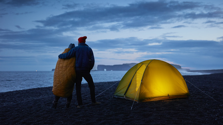 Evening campers embrace on coast.