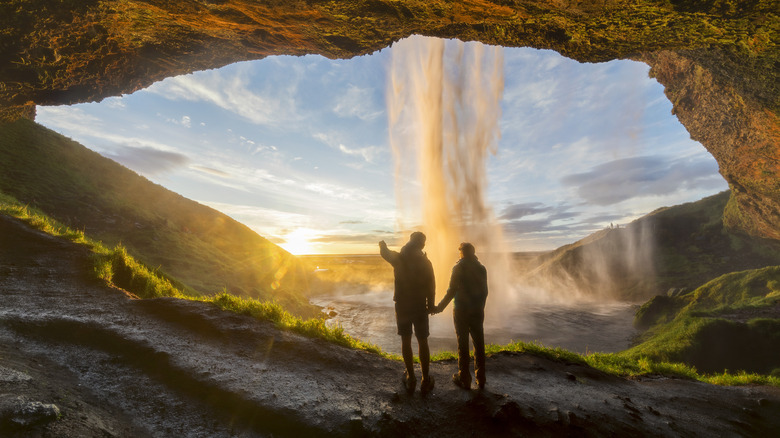 Couple watches sun from cave.