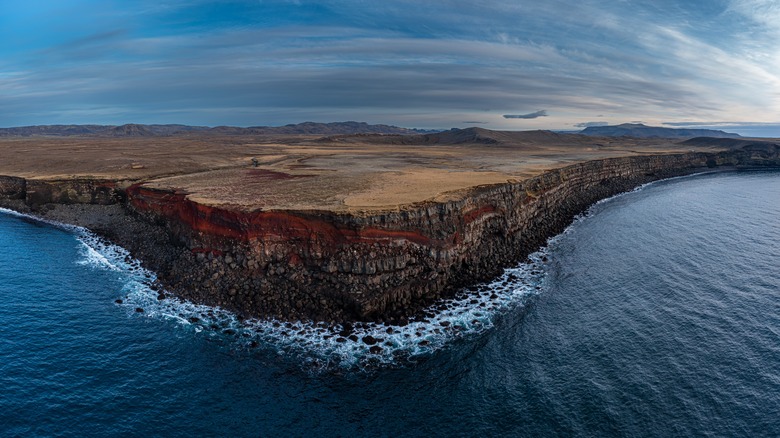 Vertical cliffs rise from ocean.