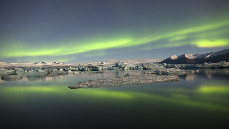 Aurora borealis glows over water.