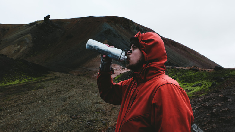person drinking water on hill