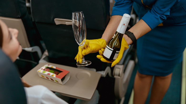 Flight attendant presenting champagne bottle