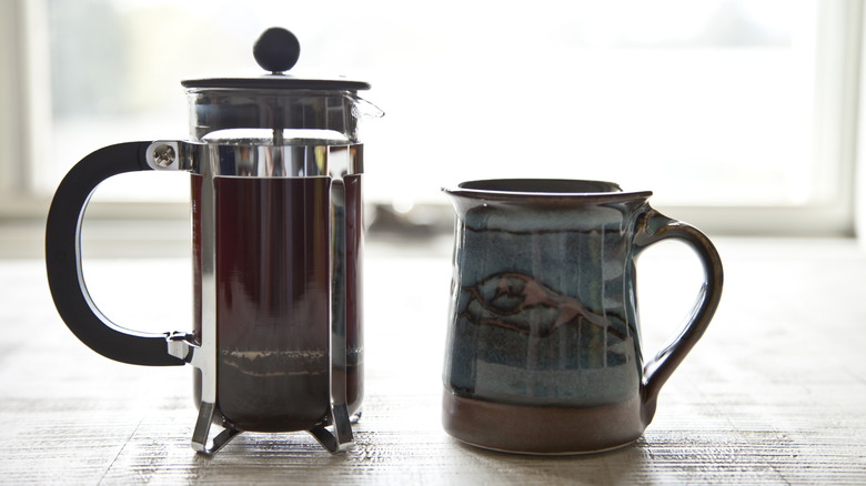 French press and coffee mug on table