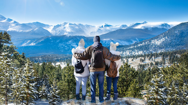 three people overlooking snowy mountains 