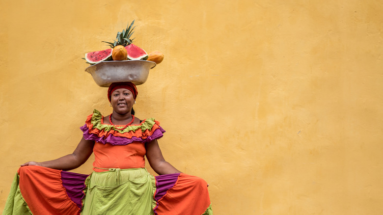 Fruit seller posing by yellow wall