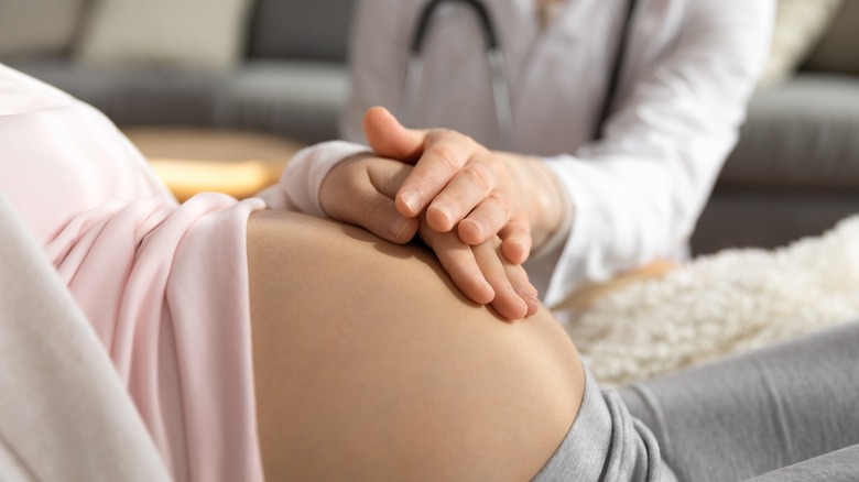 doctor feeling pregnant woman's belly