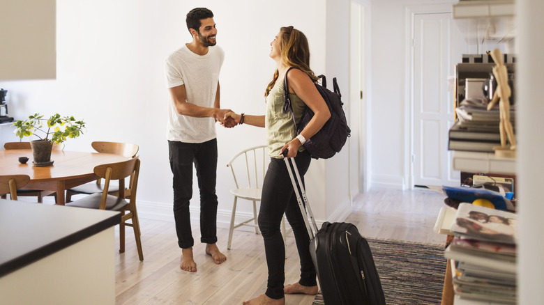 Man and woman with luggage shaking hands