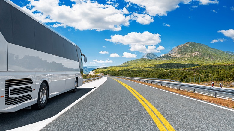 A white bus cruises on a mountain road