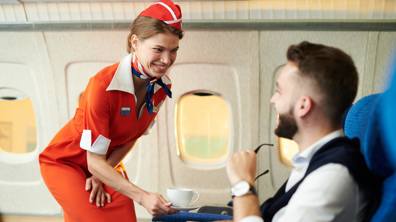 Flight attendant serving passenger coffee