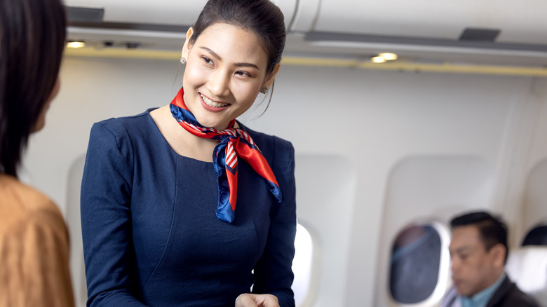 Female flight attendant helping passenger