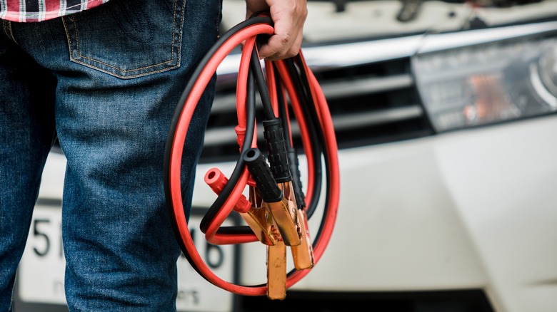 person holding car jump cables