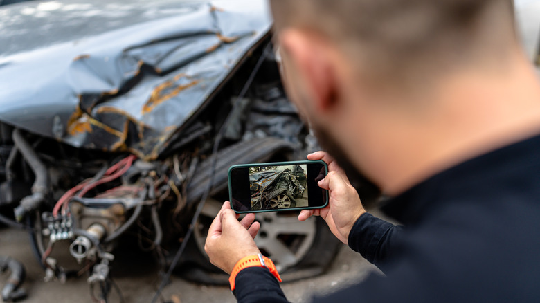 man smartphone assessing car damage 