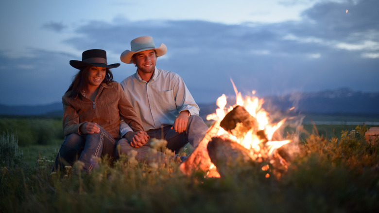 Cowboy couple sitting at campfire