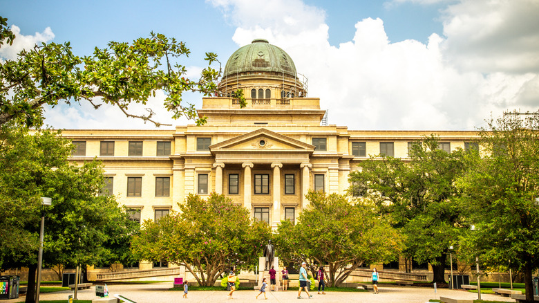 Trees and people in front of the Academic Building at Texas A&M University.