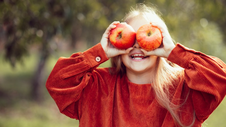 Girl holding apples on face