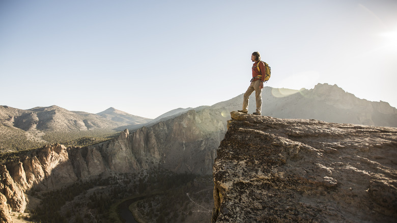 Hiking man standing on edge of a cliff