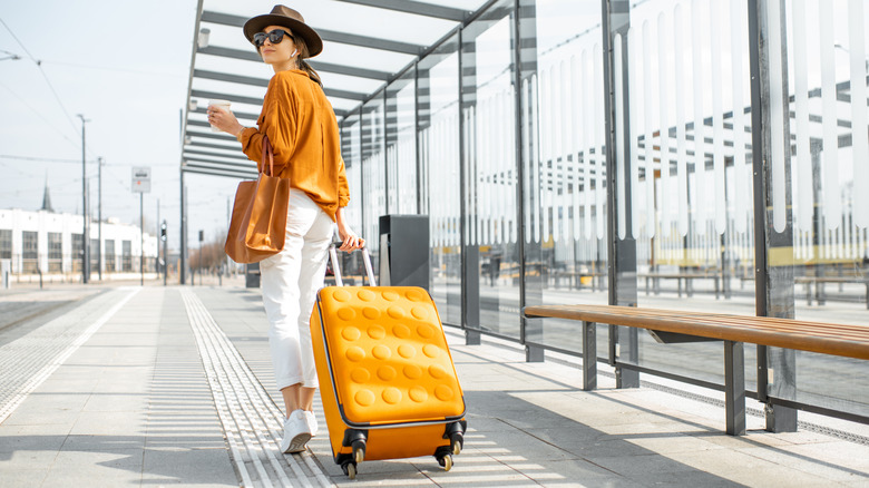 woman with suitcase at bus stop