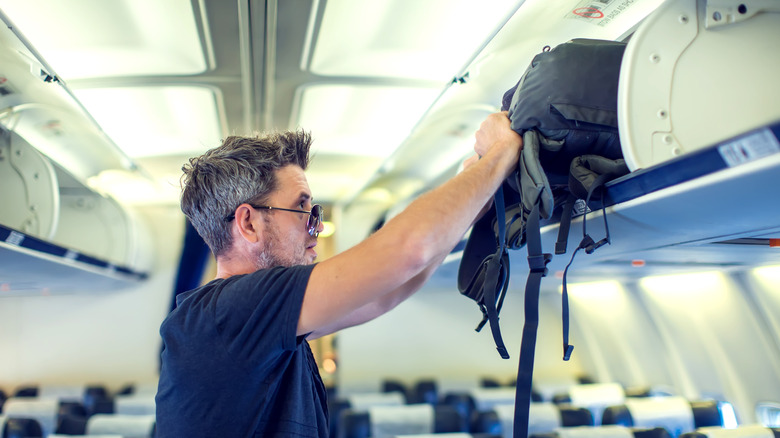 attendant helping overhead bin luggage 