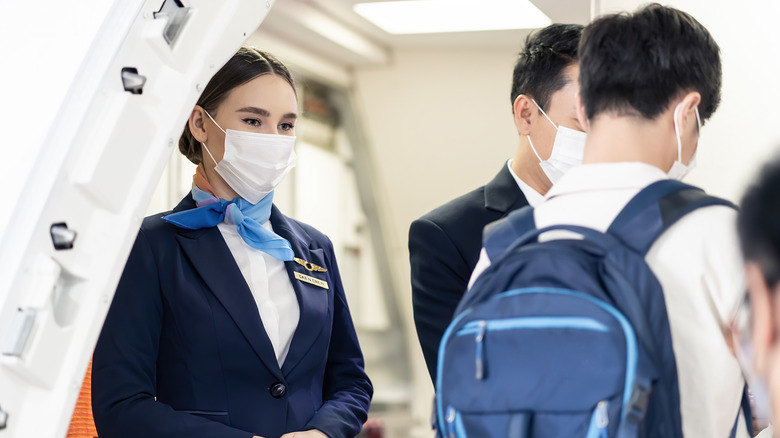 Flight attendant assisting passengers