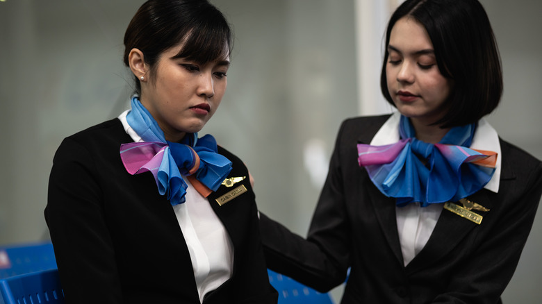 Exhausted flight attendant consoled by colleague