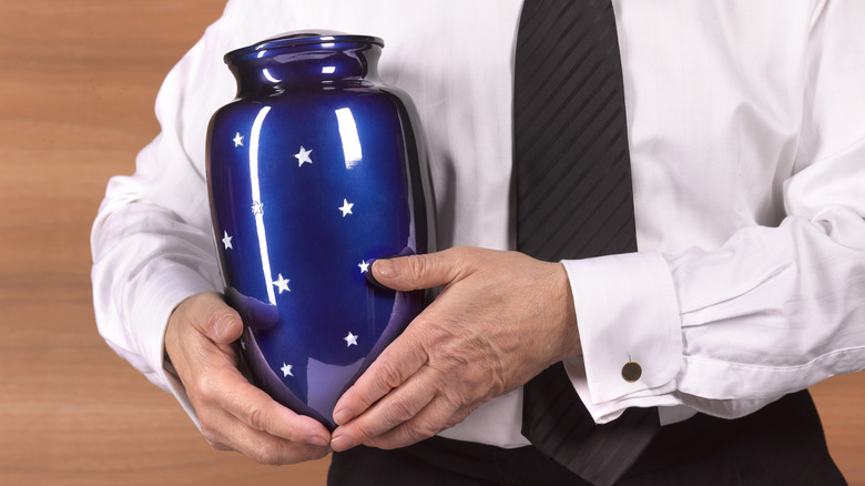 Hands holding blue urn