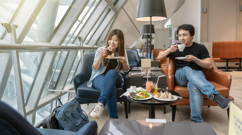 A couple eating food in an airport lounge.