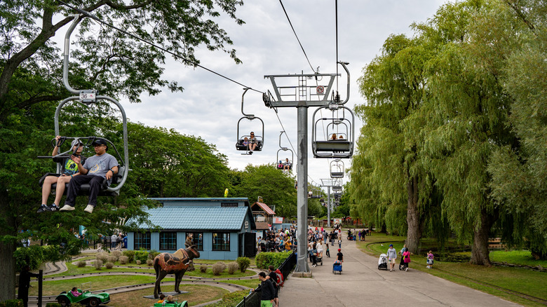 Chair lift ride over busy path at amusement park