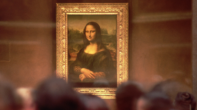 The Mona Lisa painting behind a faded crowd of observers.