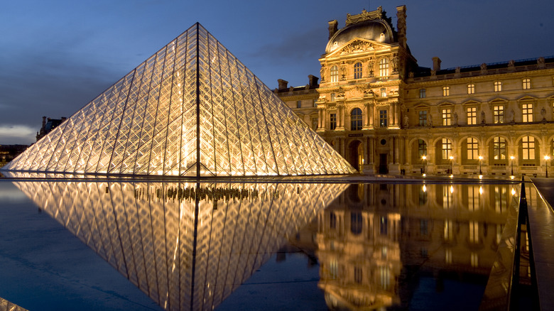 The Louvre entrance with glass pyramid at night.