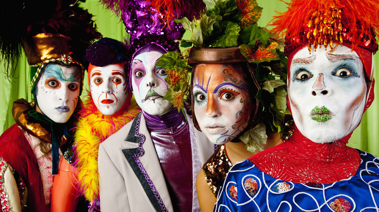 Five people pose in circus costumes and makeup