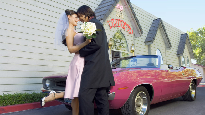 Bride and groom by pink car