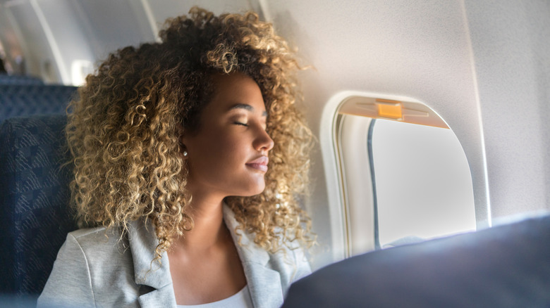 woman closing eyes on plane