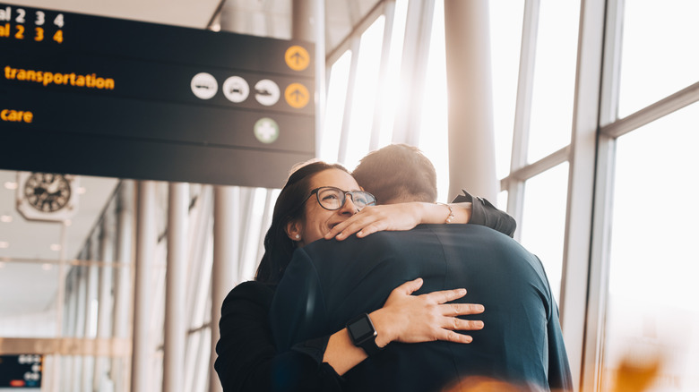 Two people hugging in an airport terminal