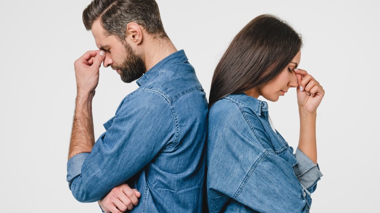 back-to-back frustrated couple pinching nose bridges