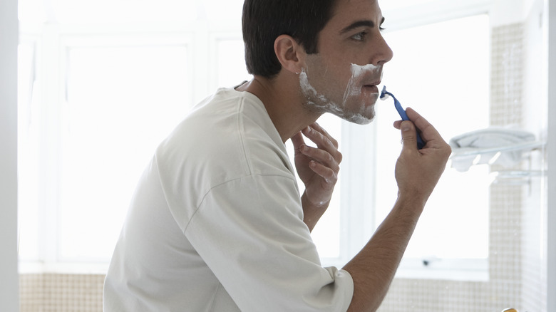 man in white shaving facial hair