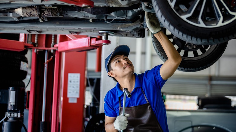 mechanic fixing car underside