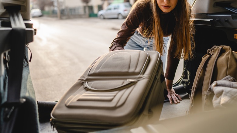 young woman packing softside suitcase