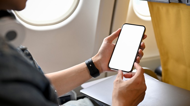 Passenger checking phone on plane