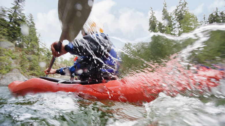 Kayaker paddling through river rapids