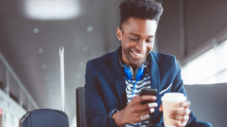 man in airport holding smartphone