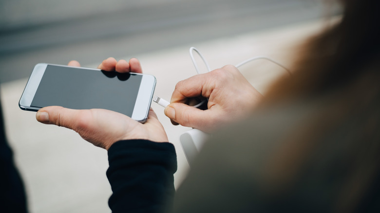 Hands plugging in phone charger