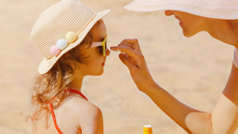 Woman applying sun protection on daughter
