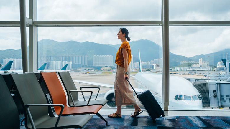 Traveler rolling suitcase through terminal