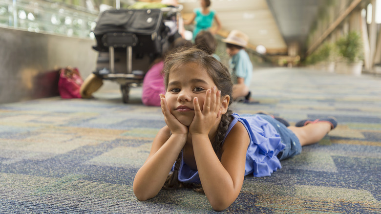 Child laying on carpeted airport floor