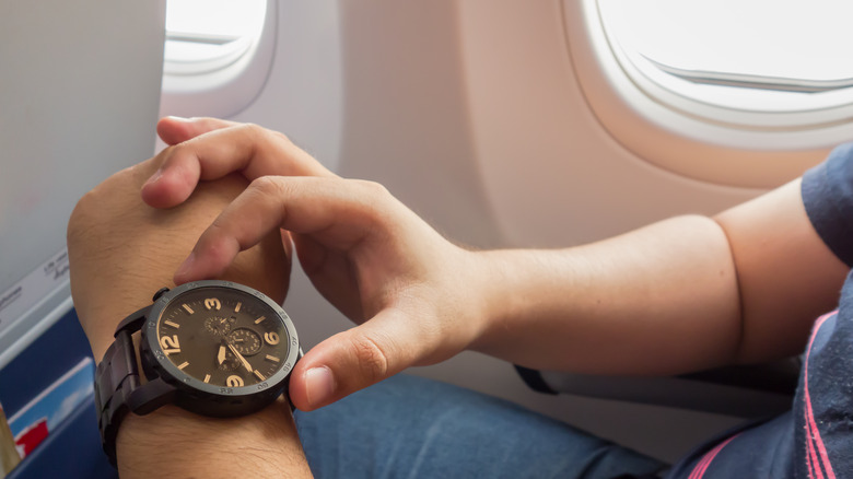 person looking at watch on airplane