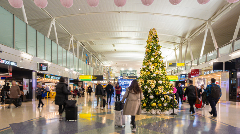 Travelers passing airport Christmas decorations