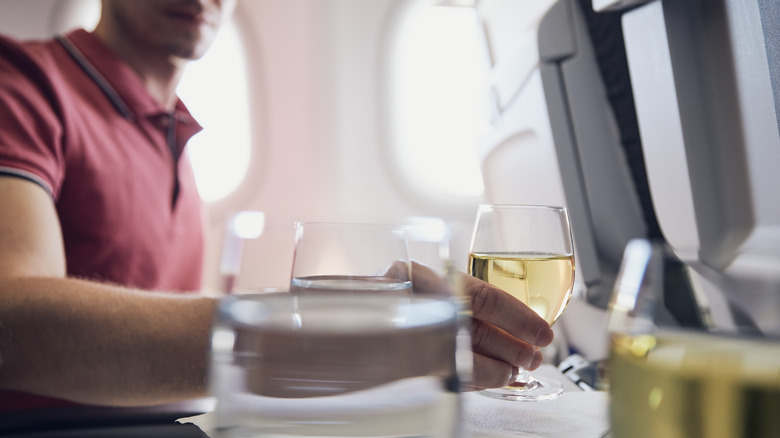 man holding wine on flight